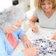 Seniorin/Rentnerin mit Hygge Betreuungskraft in Leipziger Wohnung spielen ein Puzzle zum Gedächtnistraining