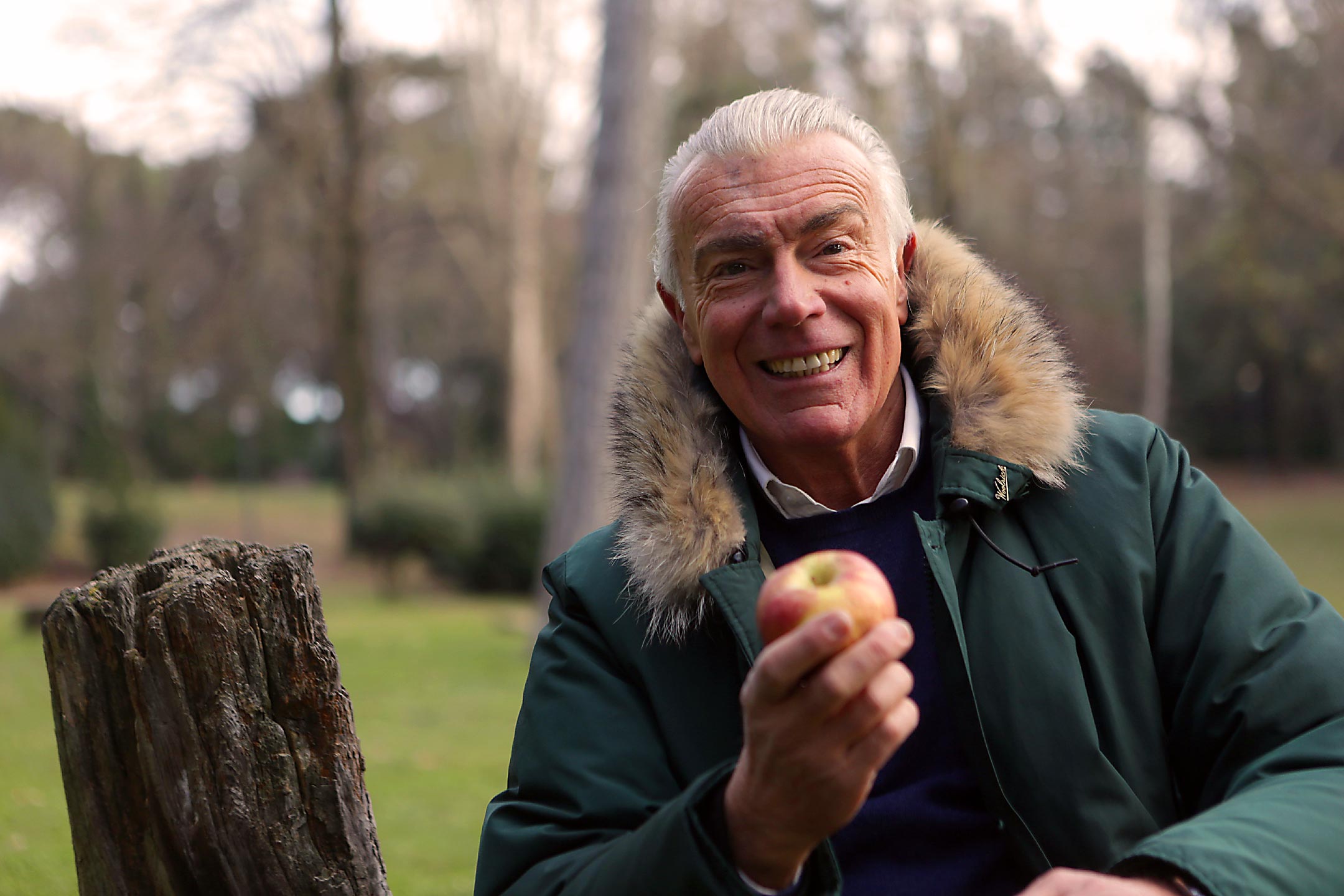Älterer Mann im Winter bei kalten Temperaturen mit einem Apfel in der Hand / So kommen Sie gut durch den Winter / Hygge Betreuung Leipzig