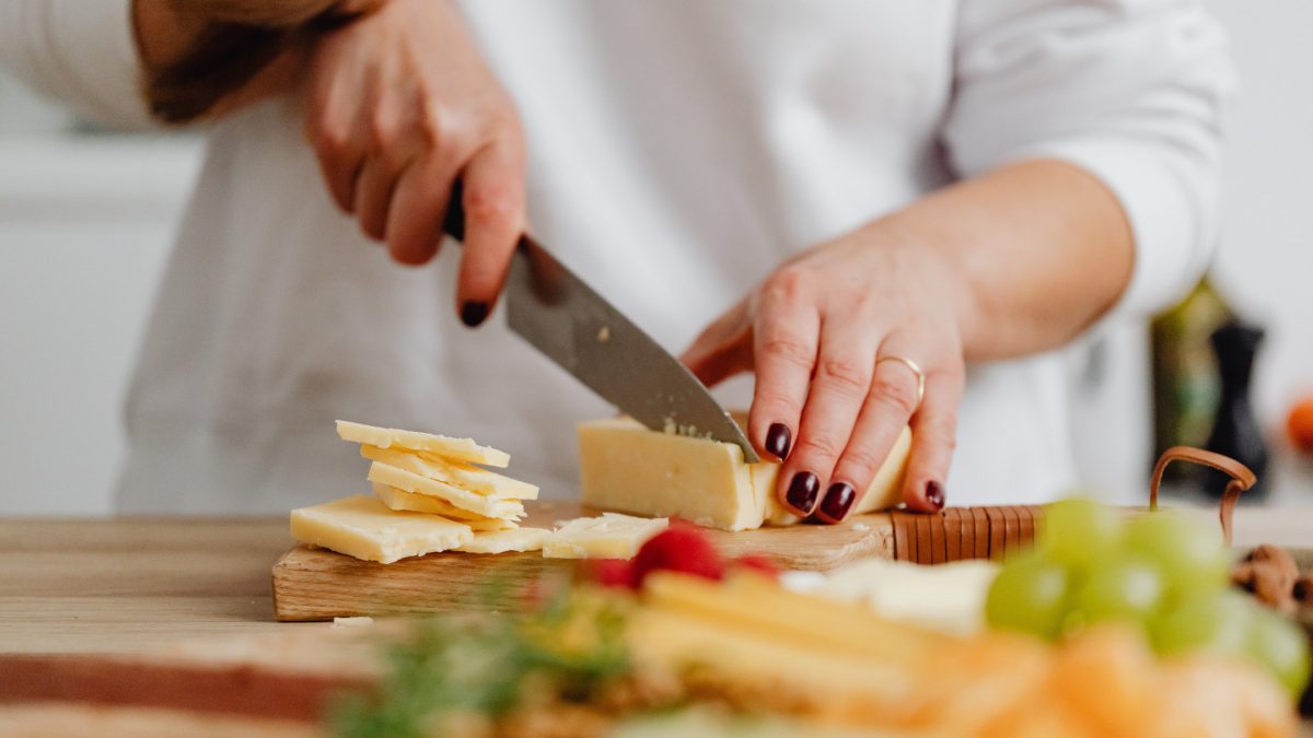 Unfälle im Haushalt: wie man sie vermeidet / Frau schneidet Käse mit scharfem Messer / Hygge Betreuung