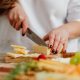 Unfälle im Haushalt: wie man sie vermeidet / Frau schneidet Käse mit scharfem Messer / Hygge Betreuung